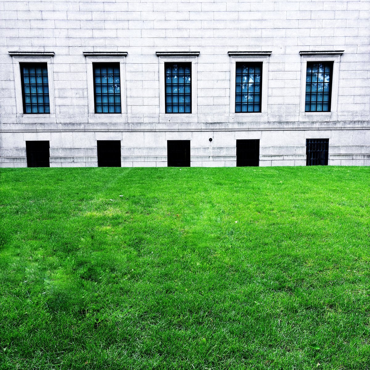 A grey stone building with five windows above a green lawn