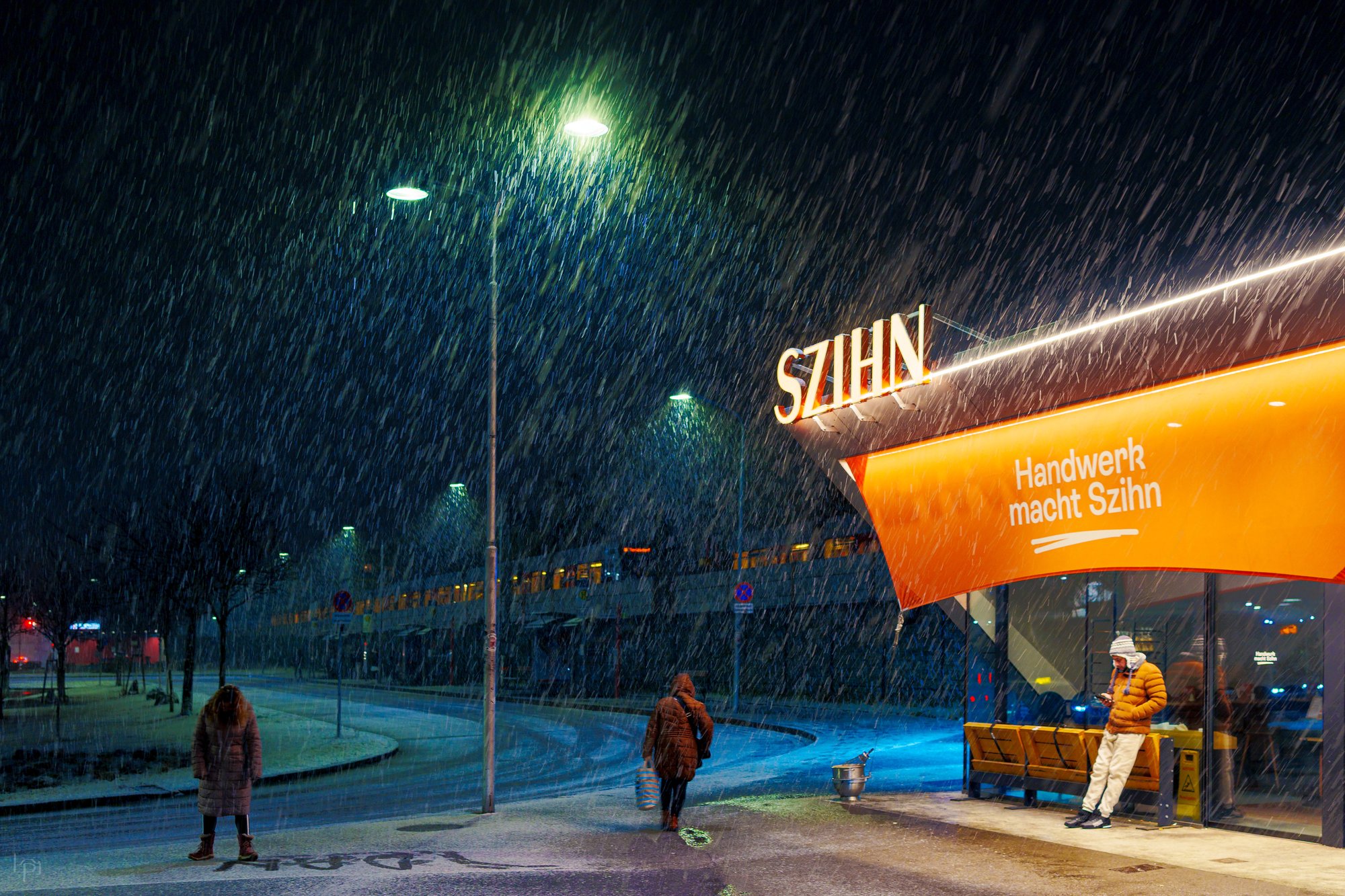 A figure walking through heavy snowfall at night, past an illuminated bus stop in Vienna